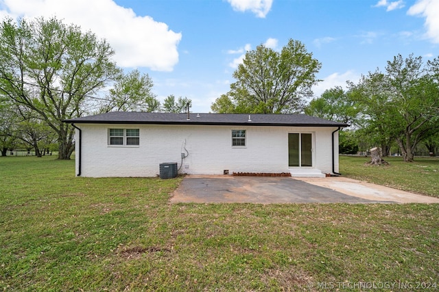 rear view of house with central AC, a lawn, and a patio area