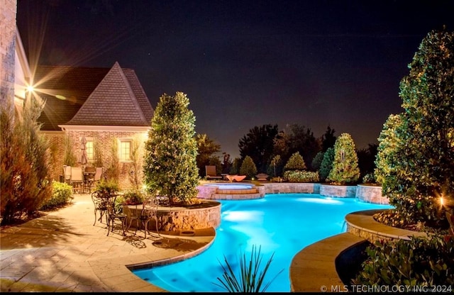 pool at twilight with an in ground hot tub and a patio