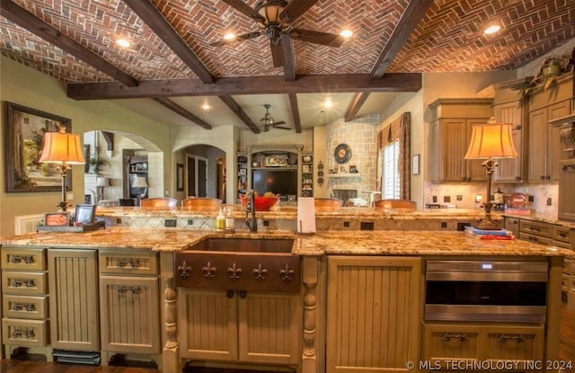 kitchen featuring light stone counters, brick ceiling, and oven