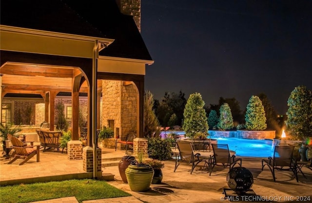 pool at twilight featuring a patio