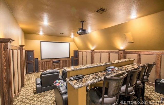 cinema room featuring lofted ceiling, light colored carpet, and a textured ceiling