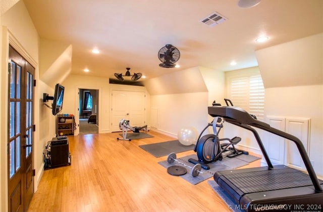 exercise area with light wood-type flooring and vaulted ceiling