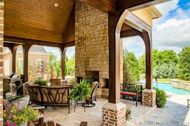 view of terrace featuring an outdoor stone fireplace and area for grilling