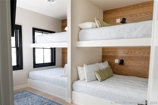 bedroom featuring light hardwood / wood-style flooring and wooden walls