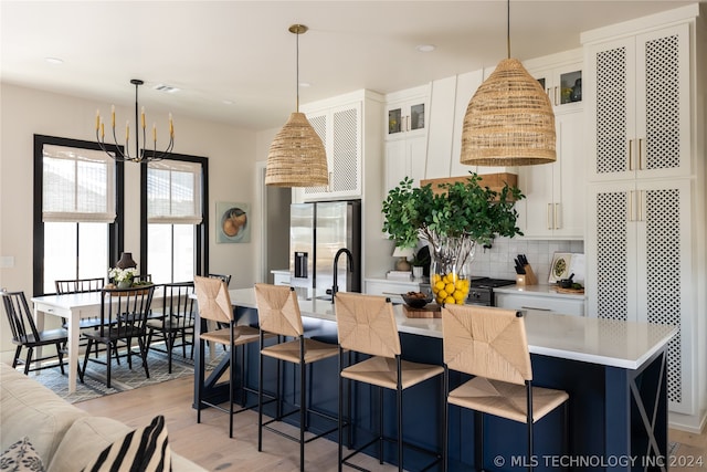 kitchen with hanging light fixtures, an island with sink, white cabinets, and stainless steel fridge with ice dispenser