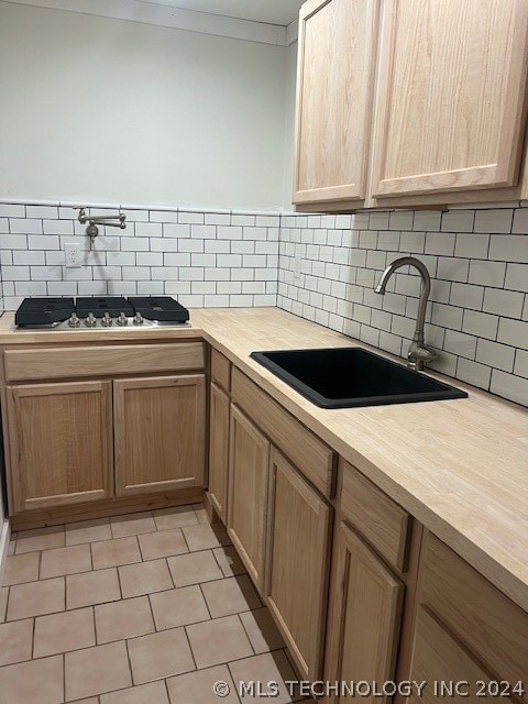 kitchen with butcher block countertops, light tile flooring, tasteful backsplash, and sink