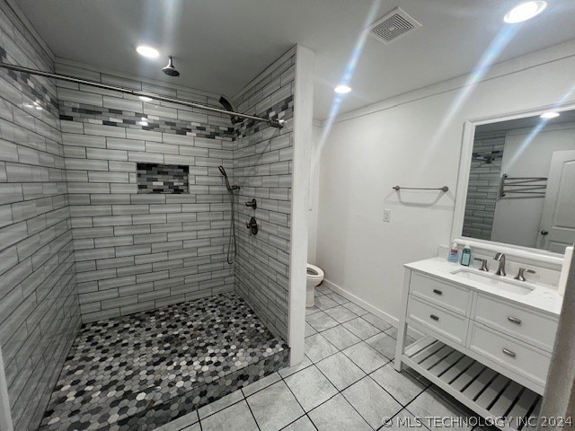 bathroom featuring tiled shower, toilet, and tile floors