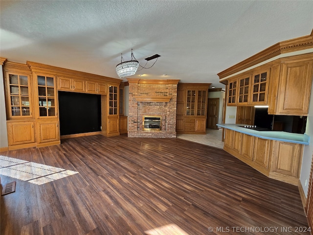 unfurnished living room with a chandelier, a fireplace, dark hardwood / wood-style floors, and a textured ceiling