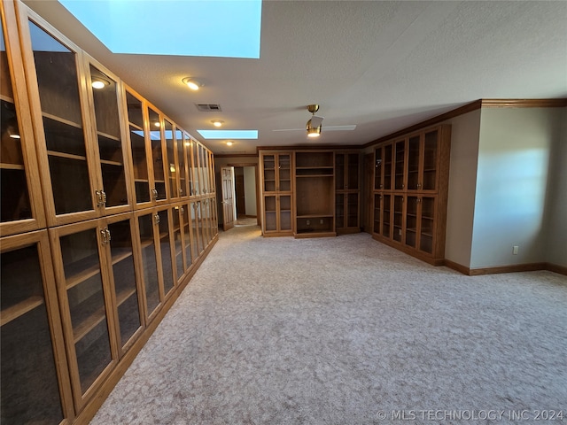 wine room with light carpet, a textured ceiling, ceiling fan, and a skylight