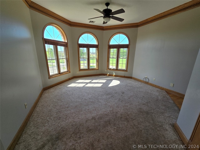 carpeted spare room featuring a healthy amount of sunlight, ceiling fan, and crown molding