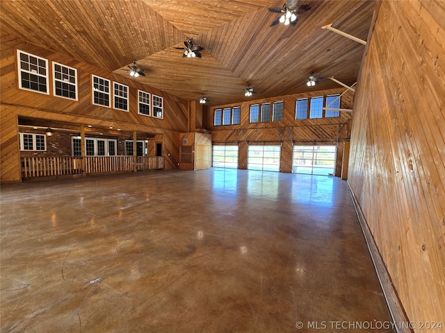 interior space with wooden walls, wooden ceiling, ceiling fan, and a high ceiling