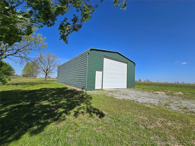 view of outdoor structure featuring a rural view, a garage, and a lawn