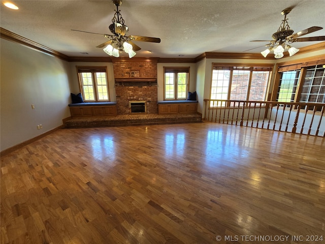 unfurnished living room featuring ceiling fan, brick wall, dark hardwood / wood-style floors, a fireplace, and ornamental molding