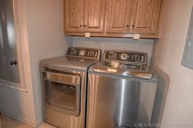 laundry room featuring washing machine and dryer, light tile flooring, and cabinets