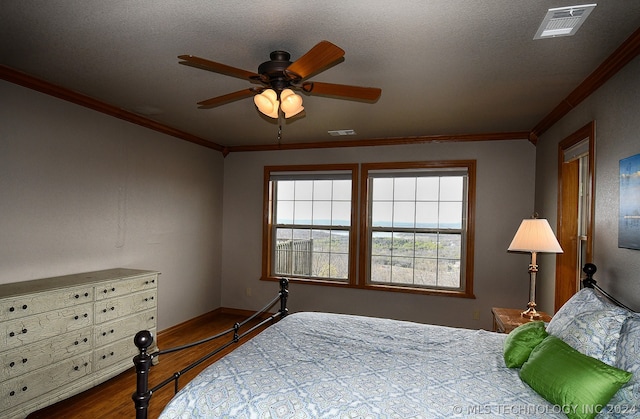 bedroom with a textured ceiling, hardwood / wood-style floors, ceiling fan, and ornamental molding