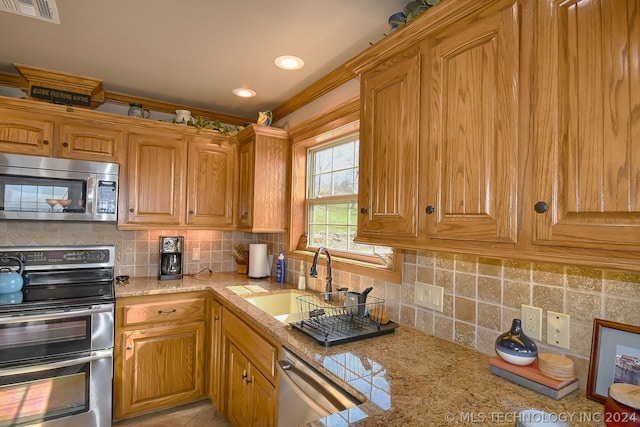 kitchen featuring backsplash, appliances with stainless steel finishes, sink, and light stone counters