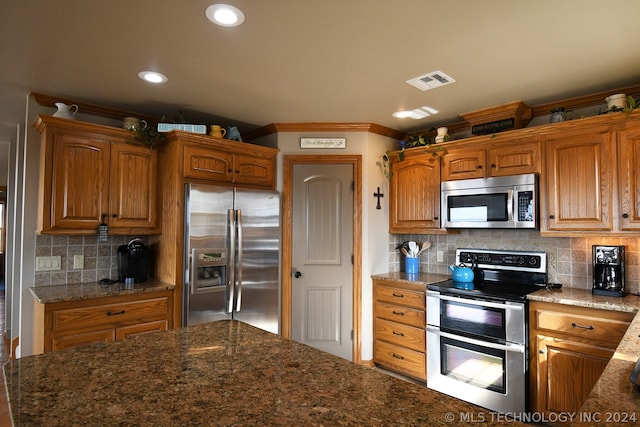 kitchen with backsplash, stainless steel appliances, dark stone counters, and crown molding