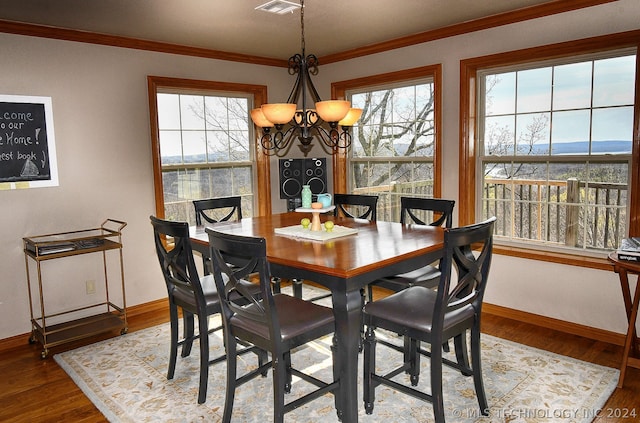 dining space featuring hardwood / wood-style flooring, a chandelier, and ornamental molding