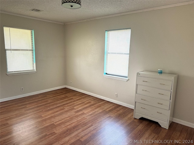 spare room featuring hardwood / wood-style floors, a textured ceiling, and ornamental molding