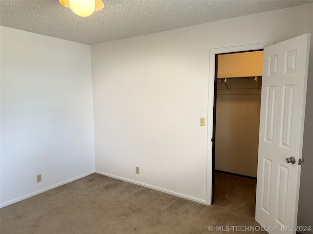 unfurnished bedroom with a walk in closet, carpet flooring, a closet, and a textured ceiling