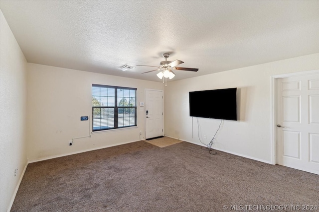 spare room featuring a textured ceiling, dark colored carpet, and ceiling fan