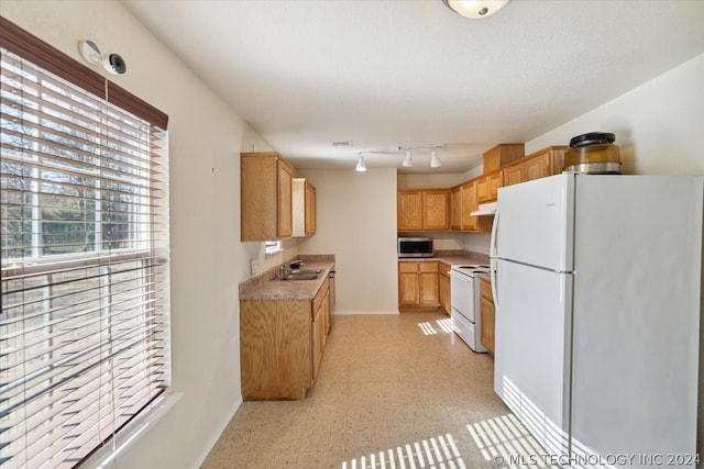 kitchen featuring rail lighting, white appliances, and sink