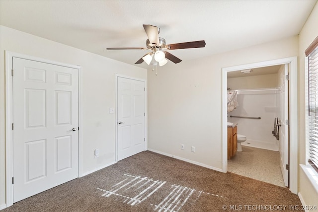 unfurnished bedroom featuring ensuite bath, ceiling fan, and dark carpet