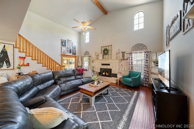 living room with high vaulted ceiling, beamed ceiling, dark hardwood / wood-style flooring, a brick fireplace, and ceiling fan