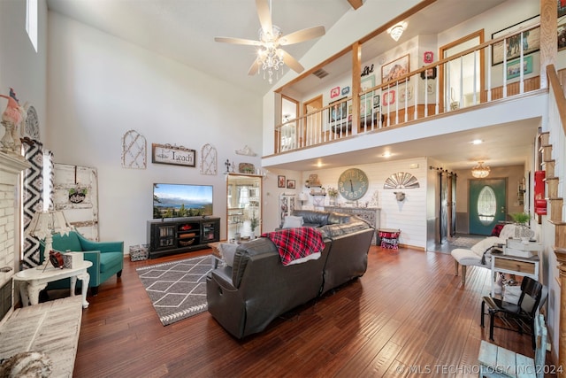 living room featuring dark wood-type flooring, ceiling fan, a high ceiling, and a fireplace