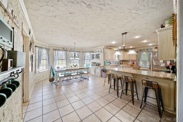 interior space featuring ornamental molding, a kitchen breakfast bar, decorative light fixtures, and light stone counters