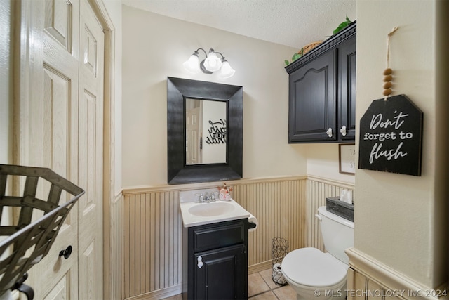 bathroom featuring tile floors, vanity with extensive cabinet space, toilet, and a textured ceiling