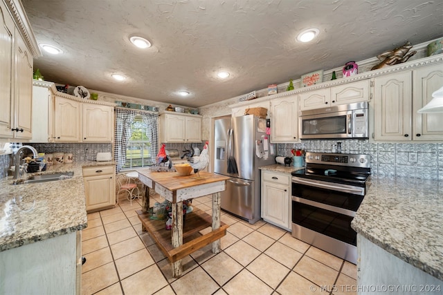 kitchen featuring appliances with stainless steel finishes, sink, tasteful backsplash, and light tile floors