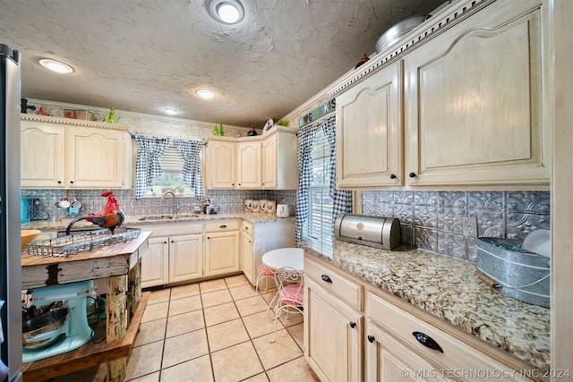 kitchen with backsplash, crown molding, light stone counters, sink, and light tile floors