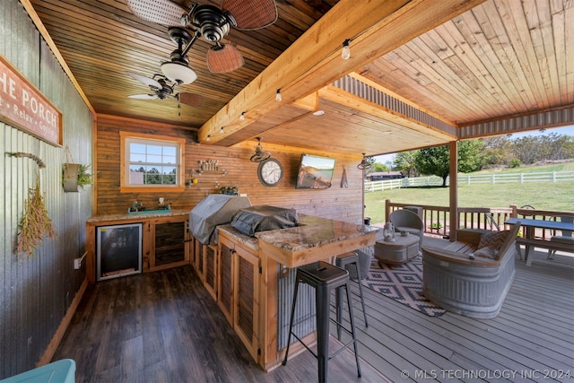 wooden terrace featuring grilling area, ceiling fan, and a bar