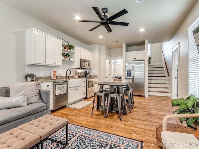 kitchen featuring white cabinetry, stainless steel appliances, light wood-type flooring, and a breakfast bar area