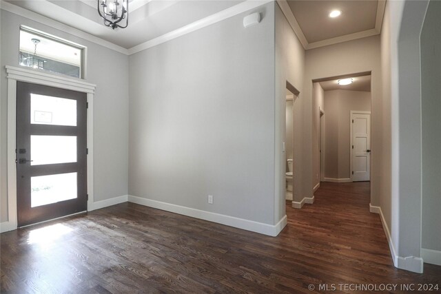 foyer featuring crown molding, dark hardwood / wood-style floors, and a chandelier