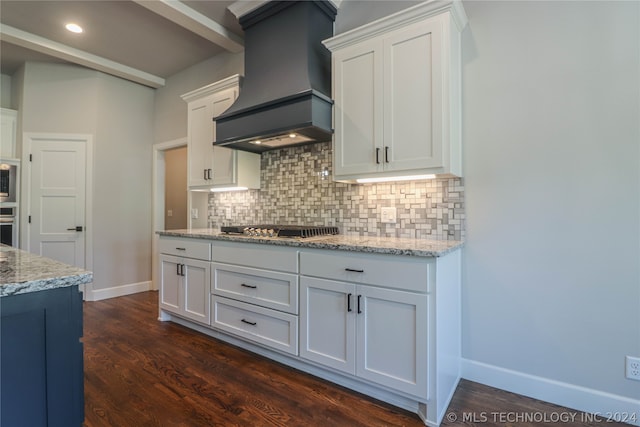 kitchen with premium range hood, white cabinetry, stainless steel appliances, light stone countertops, and decorative backsplash