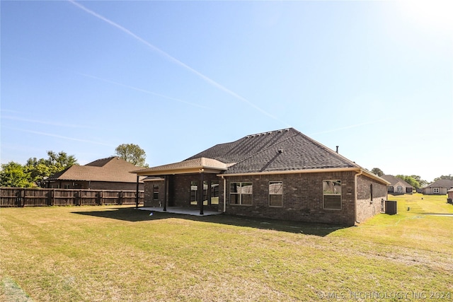 rear view of house with cooling unit, a yard, and a patio area