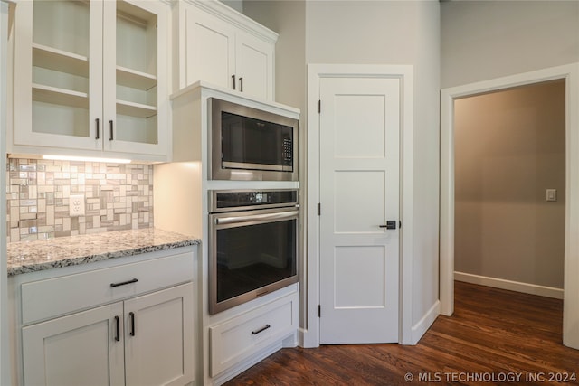 kitchen featuring built in microwave, tasteful backsplash, stainless steel oven, light stone countertops, and white cabinets