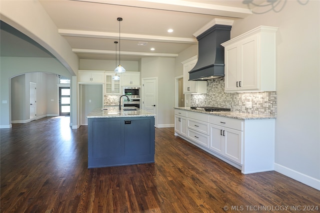 kitchen with pendant lighting, white cabinetry, stainless steel appliances, an island with sink, and custom exhaust hood