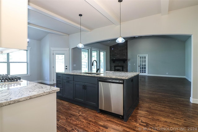 kitchen featuring sink, decorative light fixtures, lofted ceiling with beams, appliances with stainless steel finishes, and an island with sink