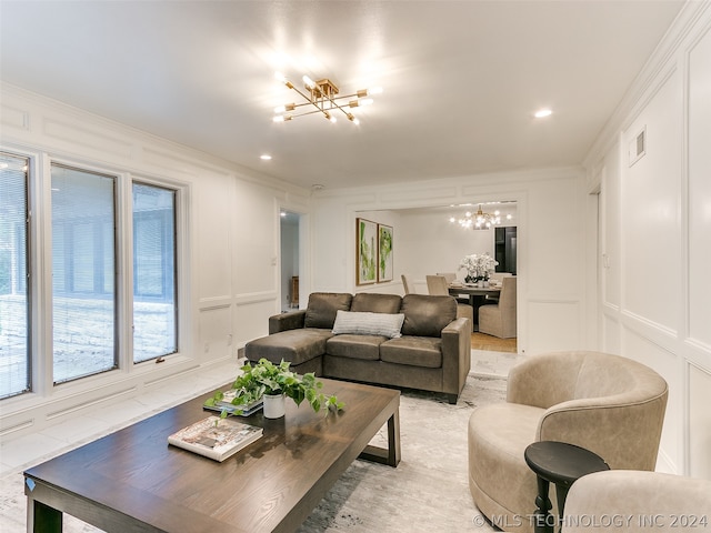 living room with a notable chandelier, light hardwood / wood-style floors, and crown molding