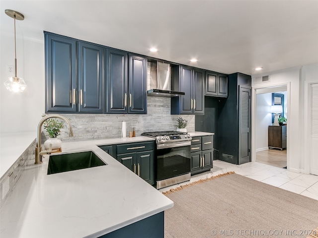 kitchen with light tile floors, sink, wall chimney range hood, decorative light fixtures, and stainless steel gas range oven