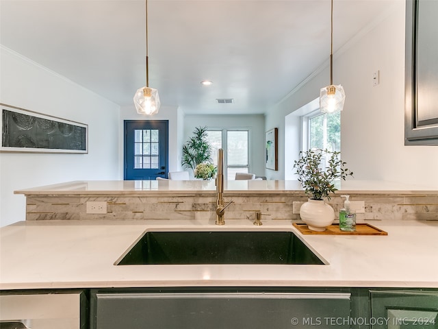 kitchen featuring sink, ornamental molding, green cabinets, and decorative light fixtures