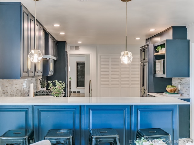 kitchen featuring backsplash, kitchen peninsula, hanging light fixtures, and a breakfast bar area