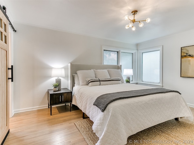 bedroom featuring a chandelier, light hardwood / wood-style floors, crown molding, and a barn door