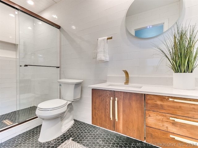 bathroom featuring tile walls, oversized vanity, toilet, an enclosed shower, and tile floors