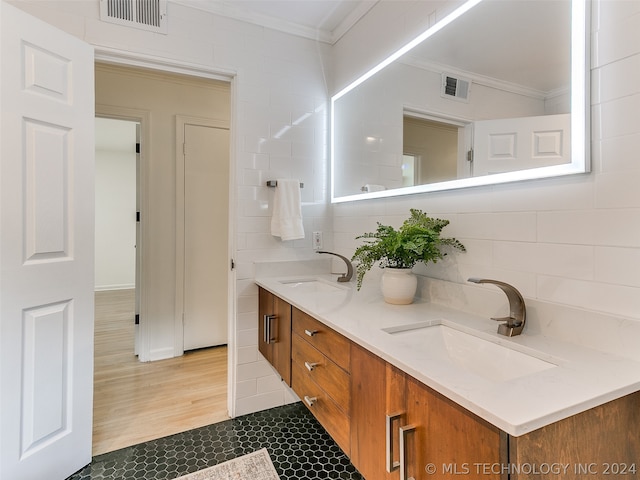 bathroom with tile walls, dual bowl vanity, hardwood / wood-style flooring, and ornamental molding