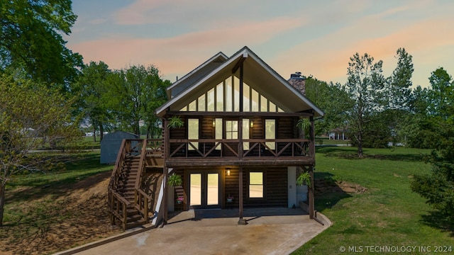 back house at dusk with a yard, a storage unit, and a patio