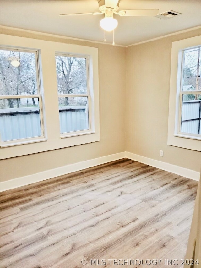 empty room with a wealth of natural light, hardwood / wood-style floors, and ceiling fan